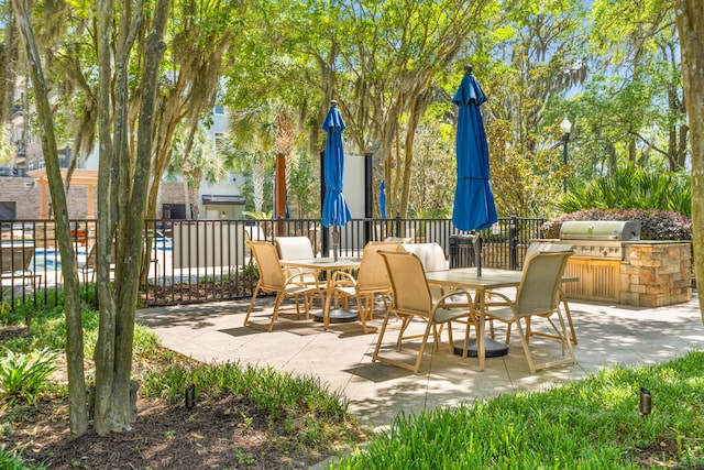 view of patio featuring outdoor dining space, fence, grilling area, and an outdoor kitchen