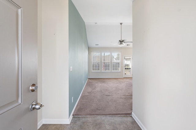 corridor featuring light tile patterned floors, baseboards, and light carpet