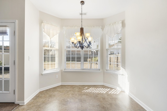 unfurnished dining area with visible vents, baseboards, and a notable chandelier