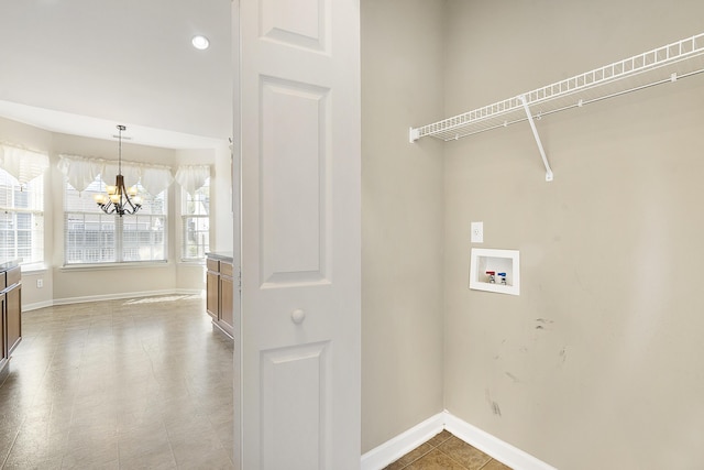 clothes washing area featuring a notable chandelier, hookup for a washing machine, laundry area, and baseboards