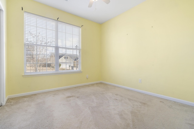 carpeted spare room featuring baseboards and ceiling fan