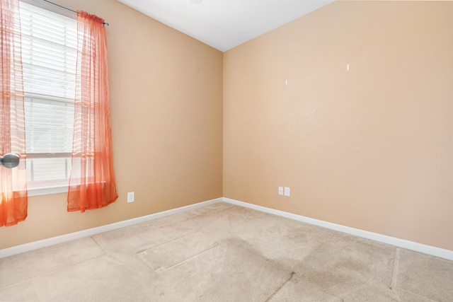 unfurnished room featuring light colored carpet and baseboards