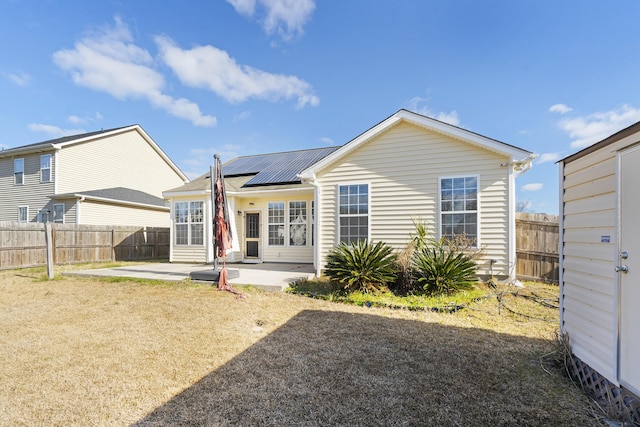 rear view of house with solar panels, a patio area, a fenced backyard, and metal roof