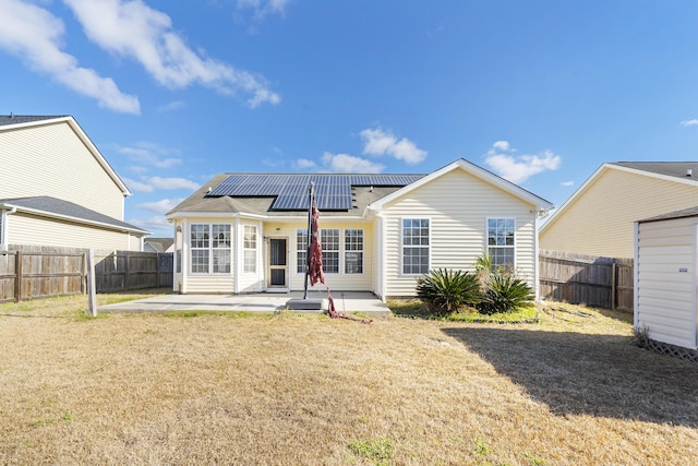 rear view of property with solar panels, a patio, a yard, and a fenced backyard