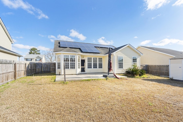 back of house featuring a yard, a patio, solar panels, and a fenced backyard