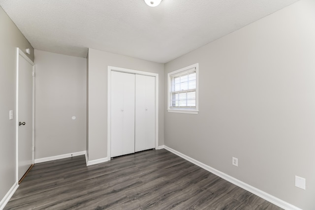 unfurnished bedroom featuring dark wood-type flooring, a closet, and a textured ceiling