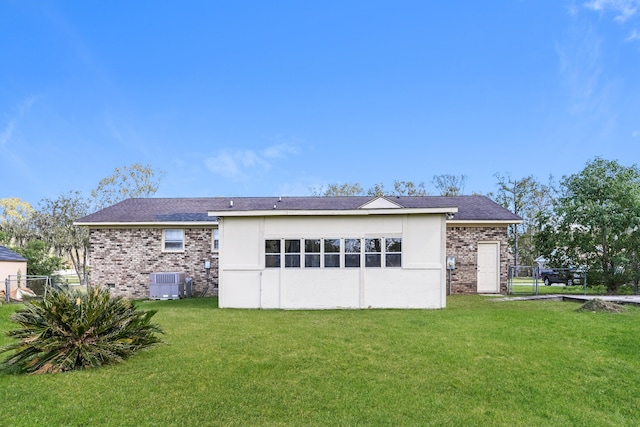 rear view of house with central air condition unit and a yard