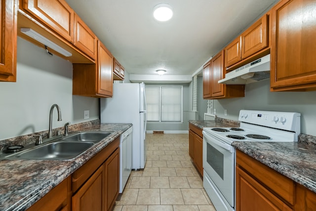 kitchen with white appliances, sink, light tile patterned floors, and dark stone counters