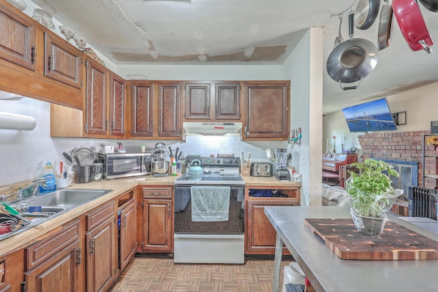 kitchen featuring white electric stove, light parquet flooring, sink, and a fireplace