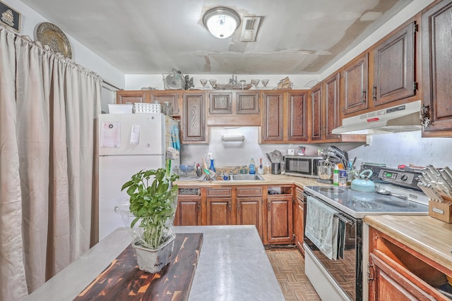 kitchen with white refrigerator, light parquet flooring, sink, and electric range oven