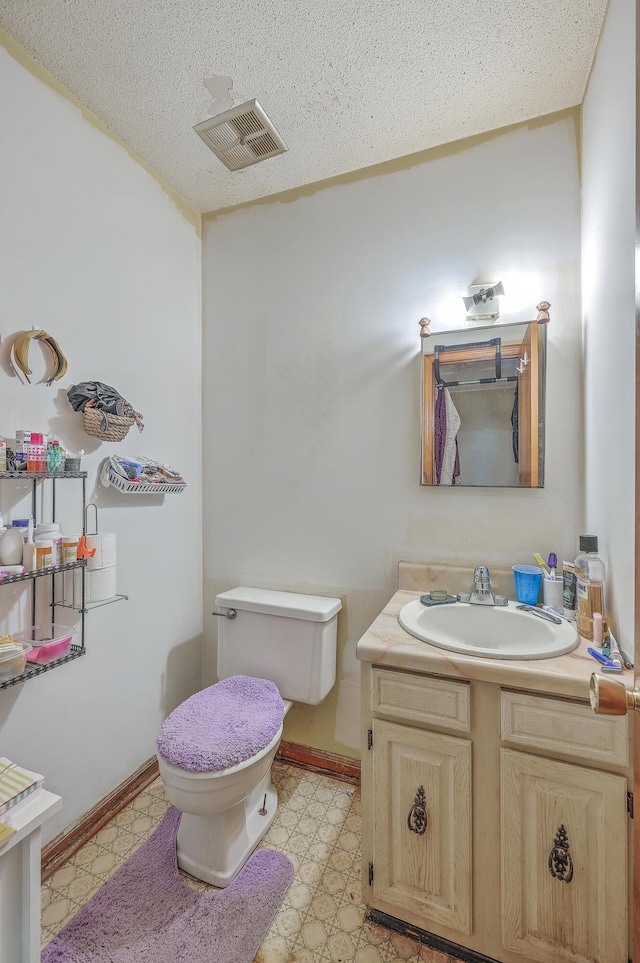 bathroom with vanity, toilet, and a textured ceiling