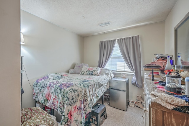 carpeted bedroom with stainless steel refrigerator and a textured ceiling