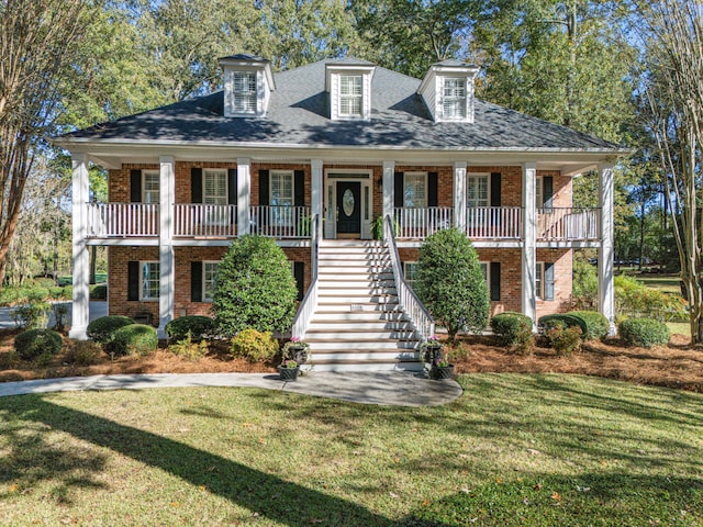 view of front of house with stairs, brick siding, a porch, and a front lawn