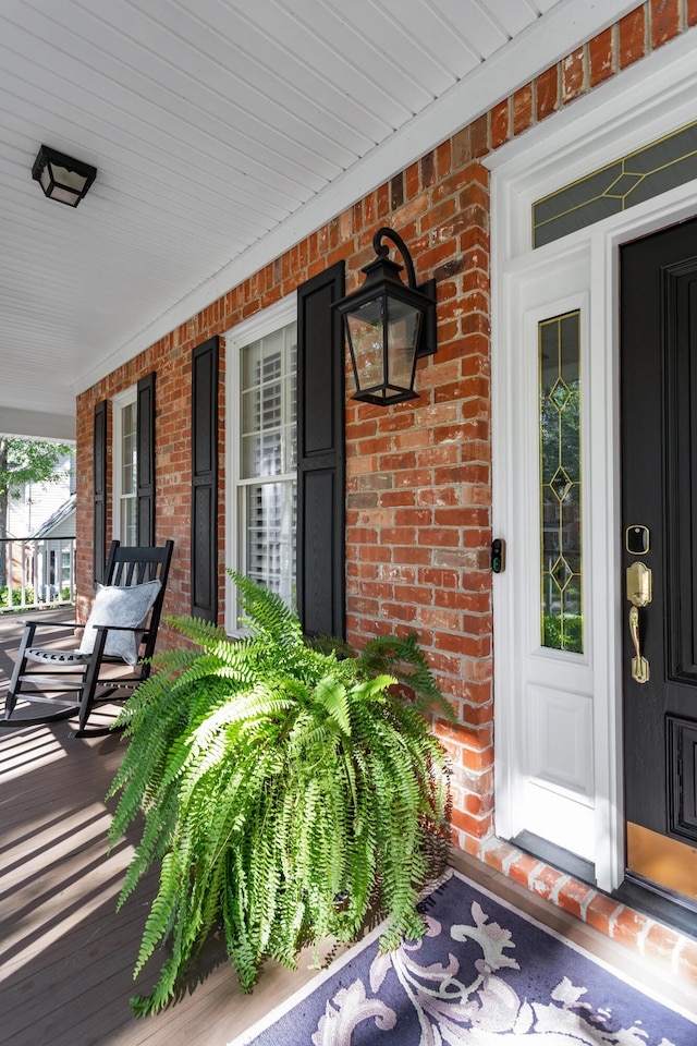 property entrance featuring a porch and brick siding