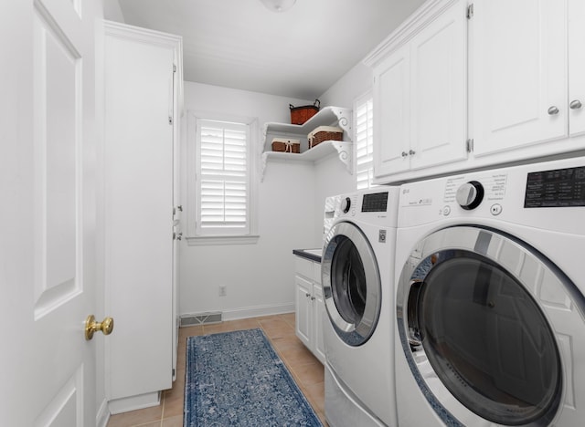 washroom featuring washer and clothes dryer, light tile patterned floors, cabinet space, and a wealth of natural light