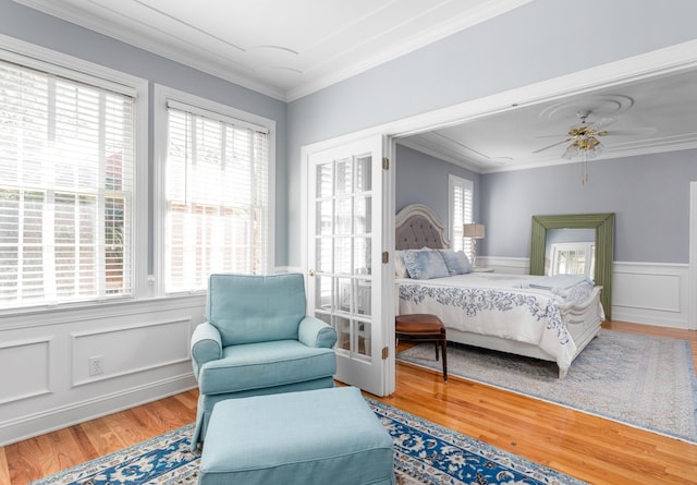 bedroom featuring ceiling fan, wood finished floors, a wainscoted wall, and ornamental molding