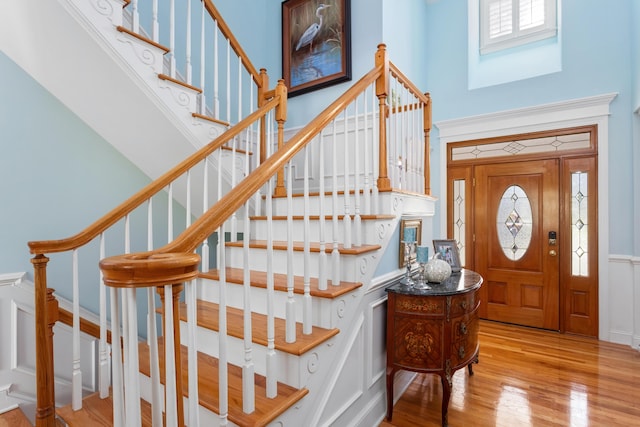 entryway featuring light wood-type flooring, a towering ceiling, and stairway