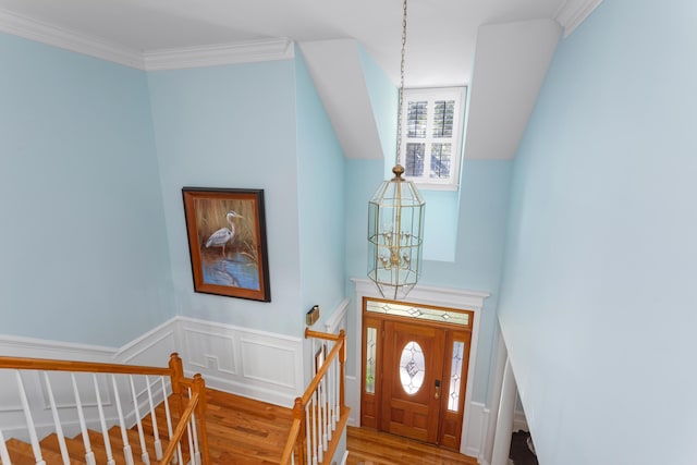 foyer entrance featuring a notable chandelier, a healthy amount of sunlight, wood finished floors, and crown molding