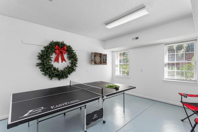 recreation room featuring visible vents, baseboards, a textured ceiling, and finished concrete floors