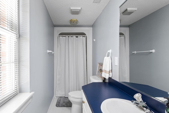 bathroom with plenty of natural light, a textured ceiling, toilet, and vanity