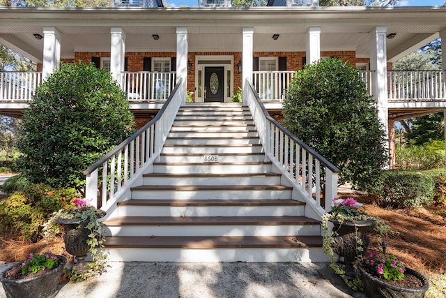 view of exterior entry with brick siding and a porch