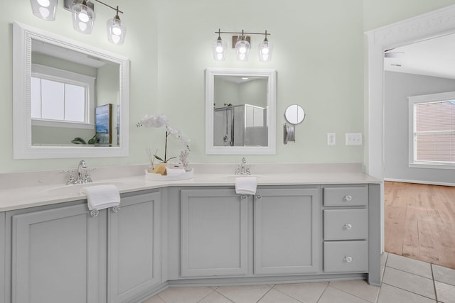 full bath with double vanity, an enclosed shower, a sink, and tile patterned floors