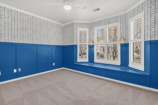 unfurnished room featuring wallpapered walls, visible vents, a ceiling fan, crown molding, and carpet flooring