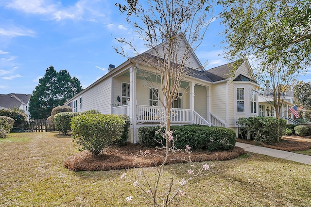 view of front facade with a porch, a front yard, and fence