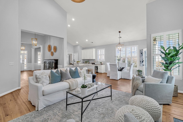 living room with an inviting chandelier, high vaulted ceiling, and light wood finished floors