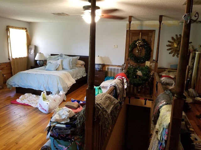 bedroom with a textured ceiling, light hardwood / wood-style flooring, and ceiling fan