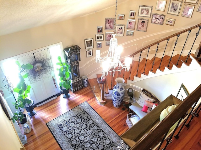 entryway with a textured ceiling, an inviting chandelier, and wood-type flooring