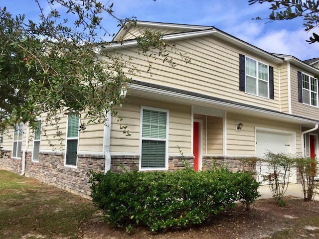 townhome / multi-family property with a garage and stone siding