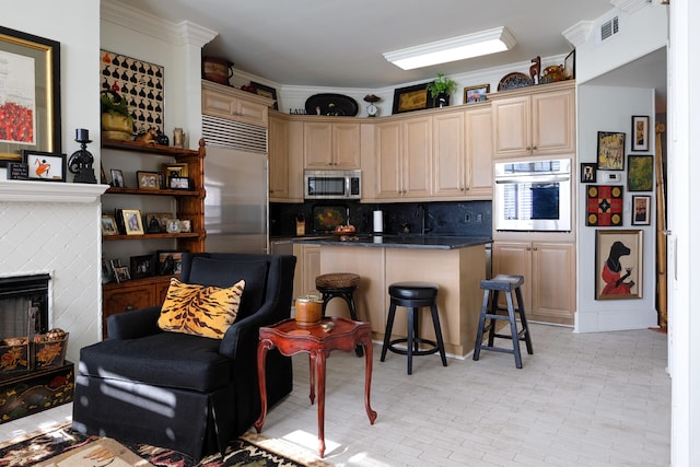 kitchen featuring a kitchen breakfast bar, backsplash, stainless steel appliances, a tile fireplace, and light brown cabinets