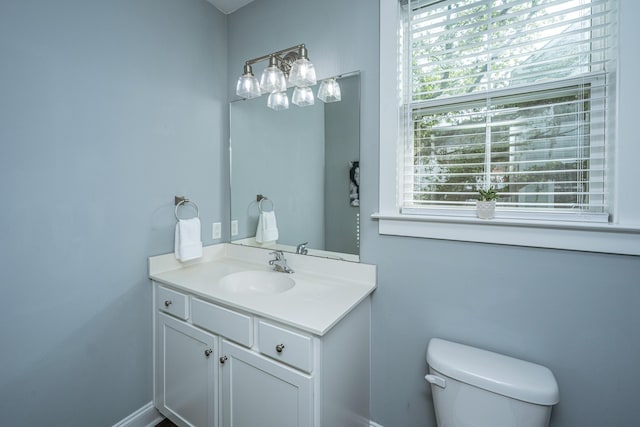 bathroom with toilet, vanity, and baseboards