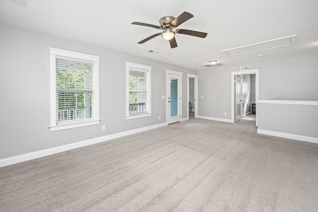 carpeted spare room featuring attic access, ceiling fan, and baseboards