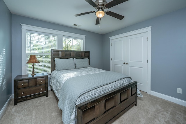 bedroom featuring light carpet, baseboards, a closet, and ceiling fan