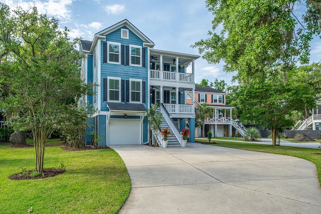 raised beach house featuring stairs, a ceiling fan, concrete driveway, a front yard, and a porch