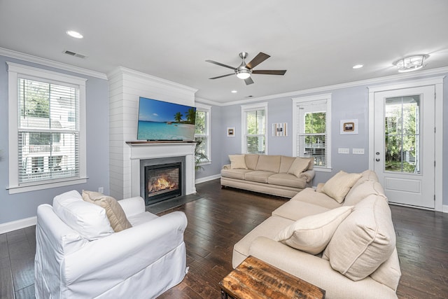living room with baseboards, ornamental molding, dark wood-style floors, a ceiling fan, and a fireplace with flush hearth