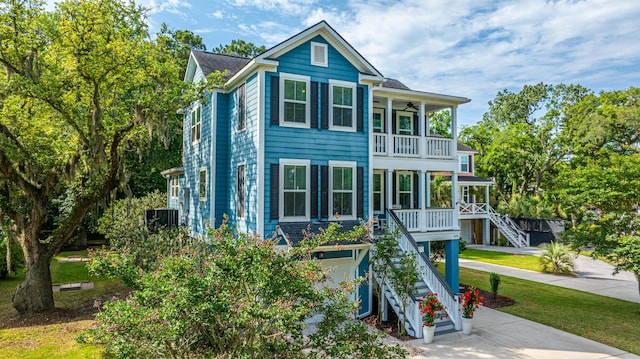 view of front of property with a balcony, a porch, stairway, concrete driveway, and ceiling fan