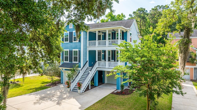 view of front of home with a balcony, a garage, driveway, stairway, and ceiling fan