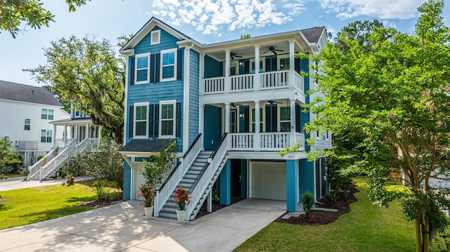 raised beach house with stairs, a ceiling fan, covered porch, and an attached garage