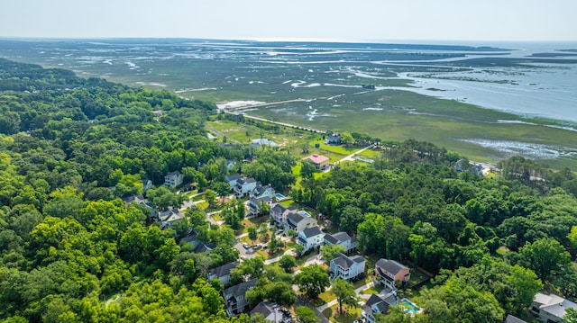 aerial view of property and surrounding area with a nearby body of water and a heavily wooded area
