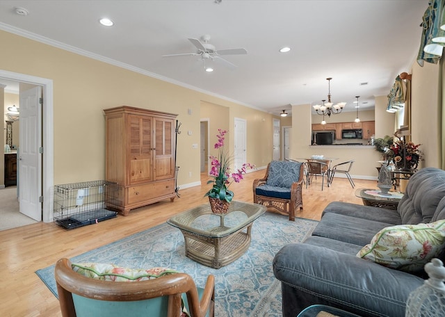 living room with ornamental molding, light hardwood / wood-style flooring, and ceiling fan with notable chandelier