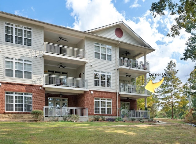 rear view of property with ceiling fan, a lawn, and a balcony