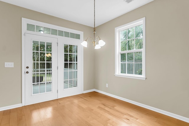 interior space with light wood-style floors, baseboards, and an inviting chandelier