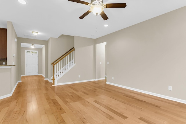 interior space with stairway, light wood-type flooring, a ceiling fan, and baseboards