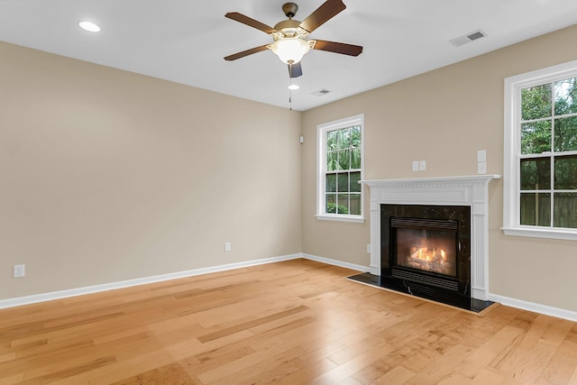 unfurnished living room featuring a high end fireplace, visible vents, plenty of natural light, and light wood-style flooring