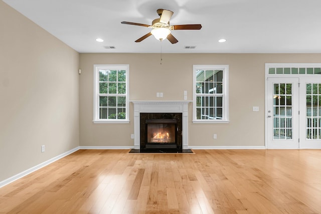 unfurnished living room with light wood-style flooring, visible vents, baseboards, and a high end fireplace