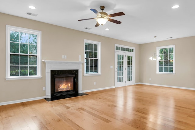 unfurnished living room with light wood finished floors, a premium fireplace, visible vents, and a healthy amount of sunlight