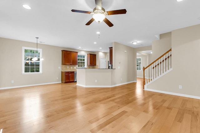 unfurnished living room featuring stairs, light wood finished floors, and a wealth of natural light